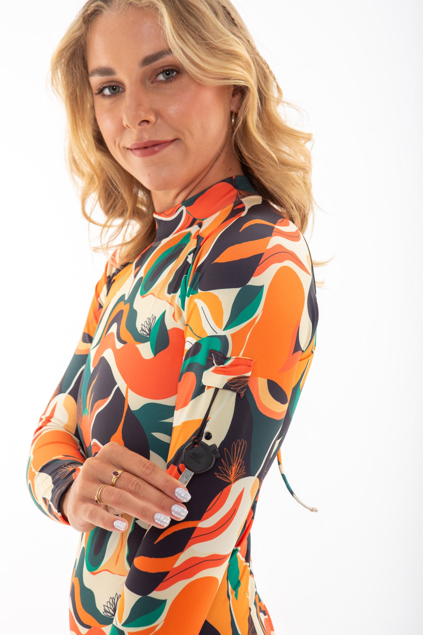 A woman wearing the Made Long Sleeve One-Piece Surf Spring Suit with colourful print, showcasing the key pocket in the arm
