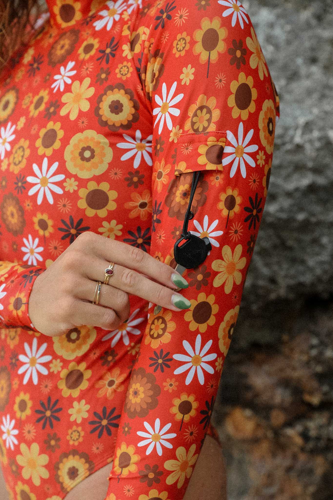 Model holding the key that is hanging on a key loop of her surf suit in retro floral print