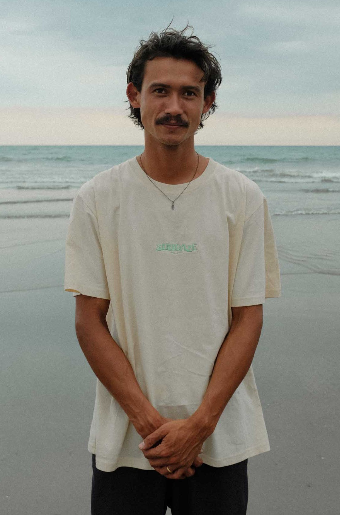 Male standing at the beach and wearing the SunDaze Tee