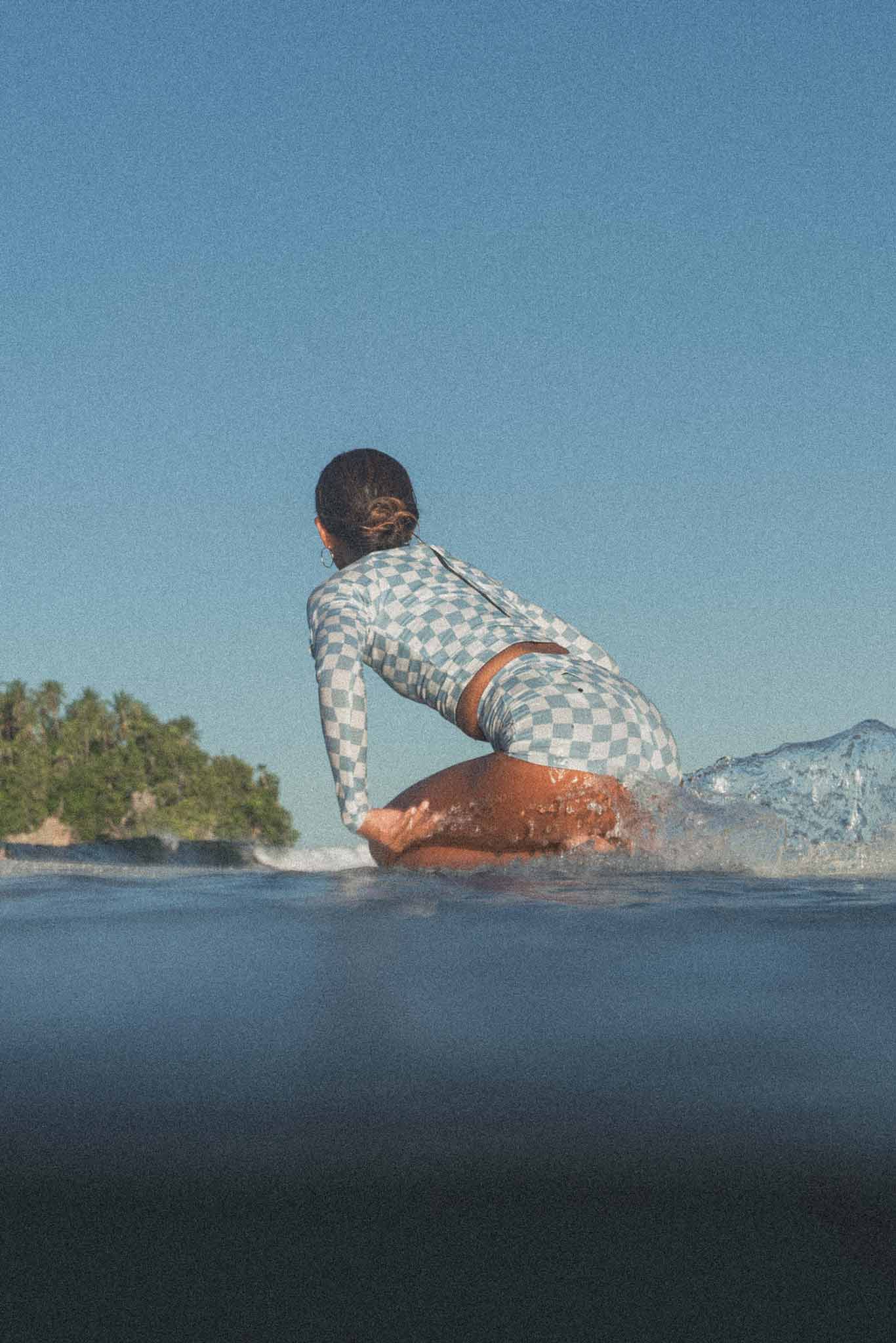 Woman padling on a longboard wearing a retro checkered print set