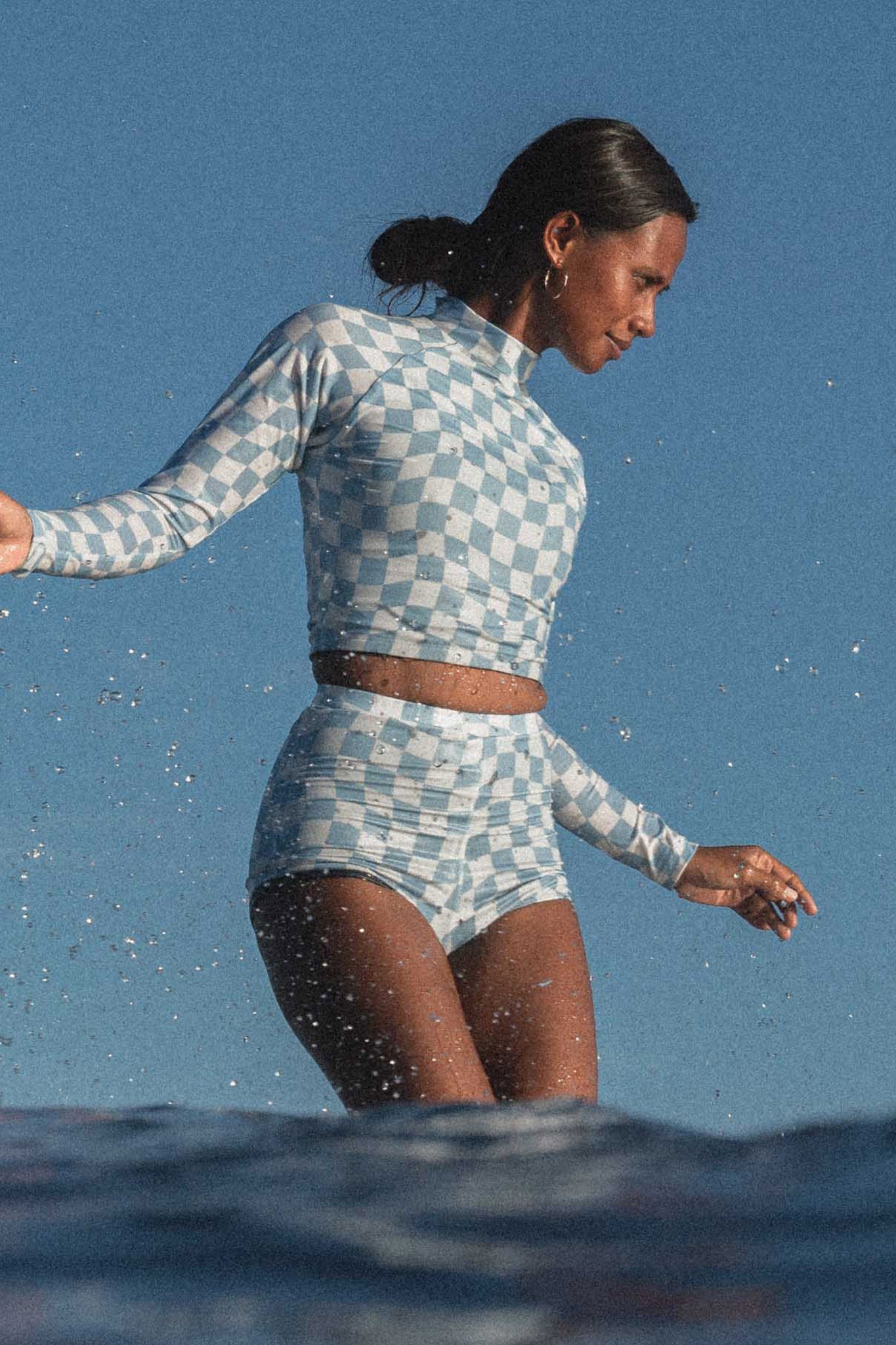 Woman surfing and wearing the putu set in blue check