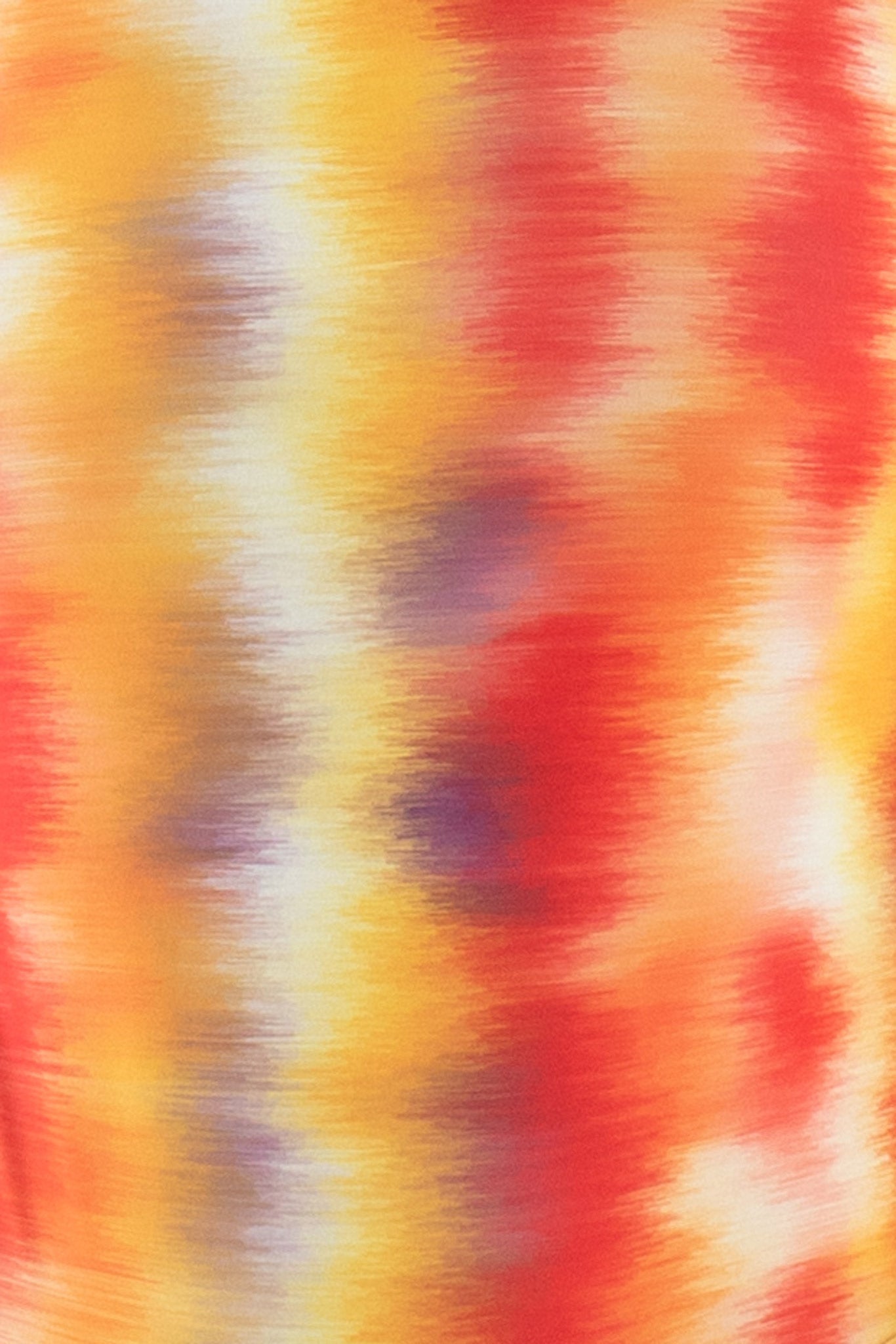 Close-up detail of the tie dye print on the Wayan Sleeveless One-Piece Surf Spring Suit in red, yellow, and orange hues