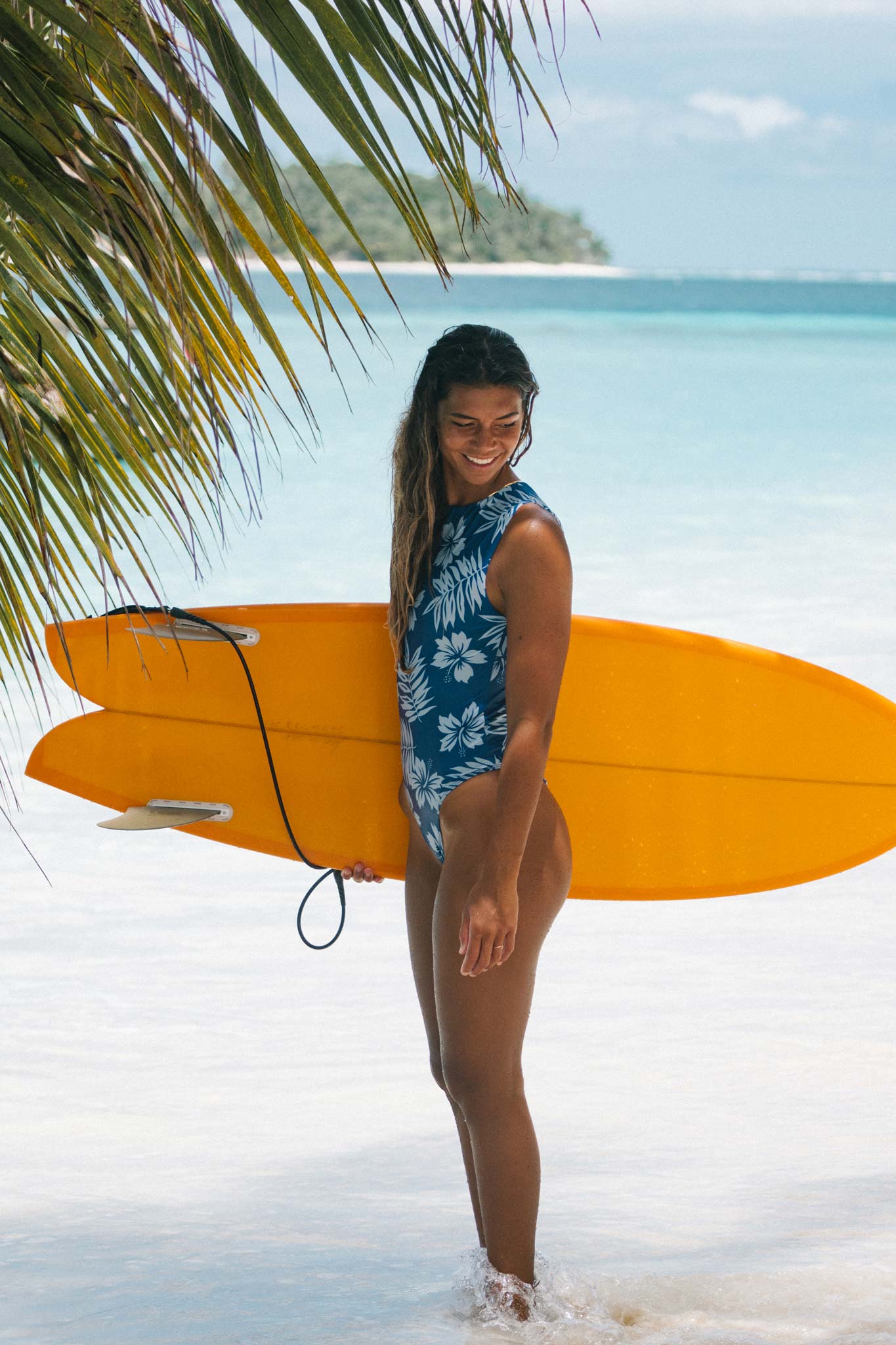 Model walking on the beach wearing the blue hibiscus surf suit view from the side