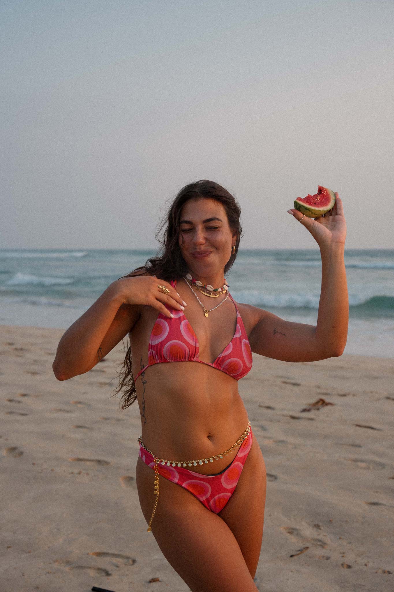model posing at the beach with a watermelon in her hand