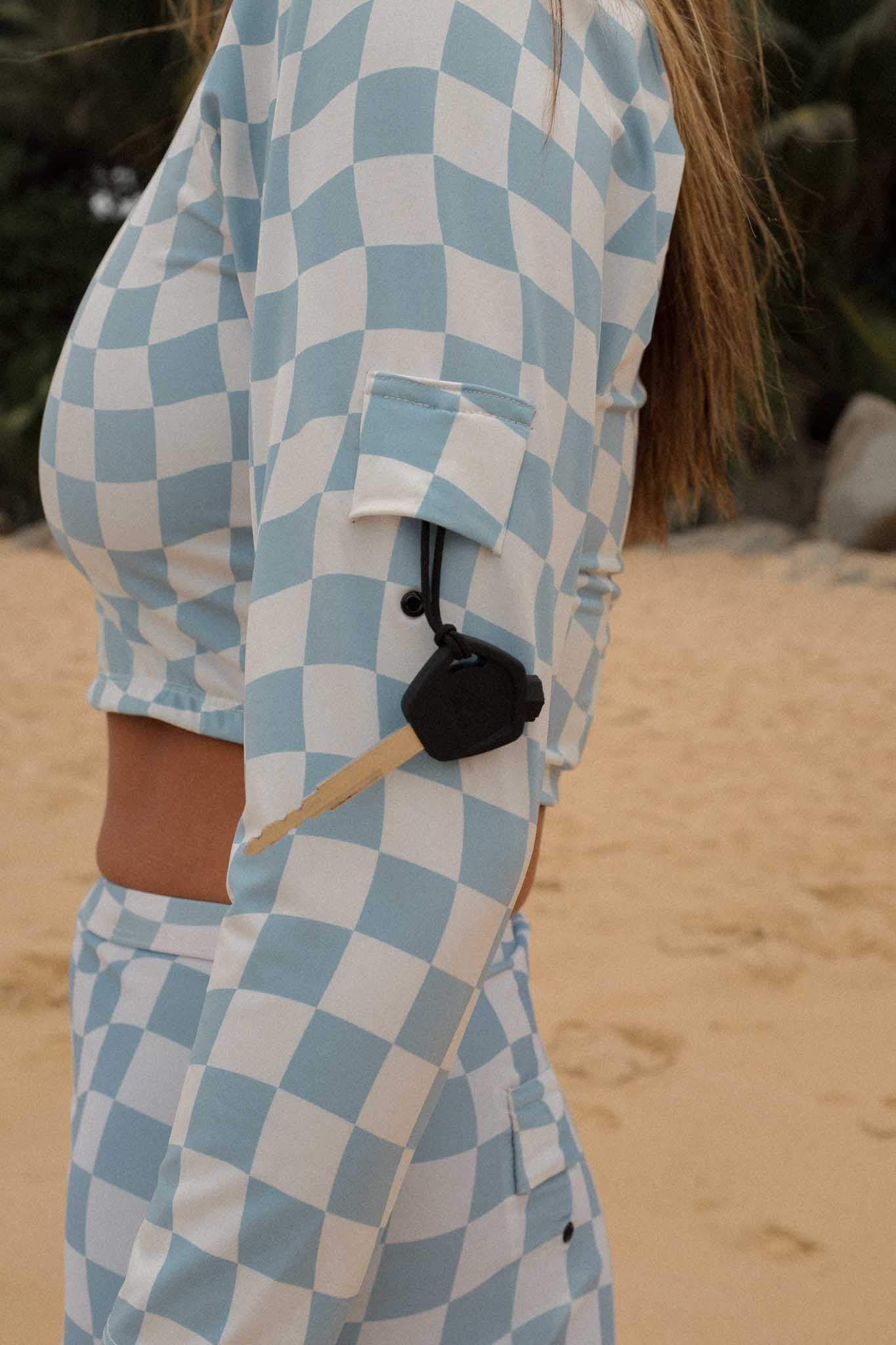 A woman showcasing the Putu Scoop Neck Surf Rashie Top with a key pocket on the sleeve