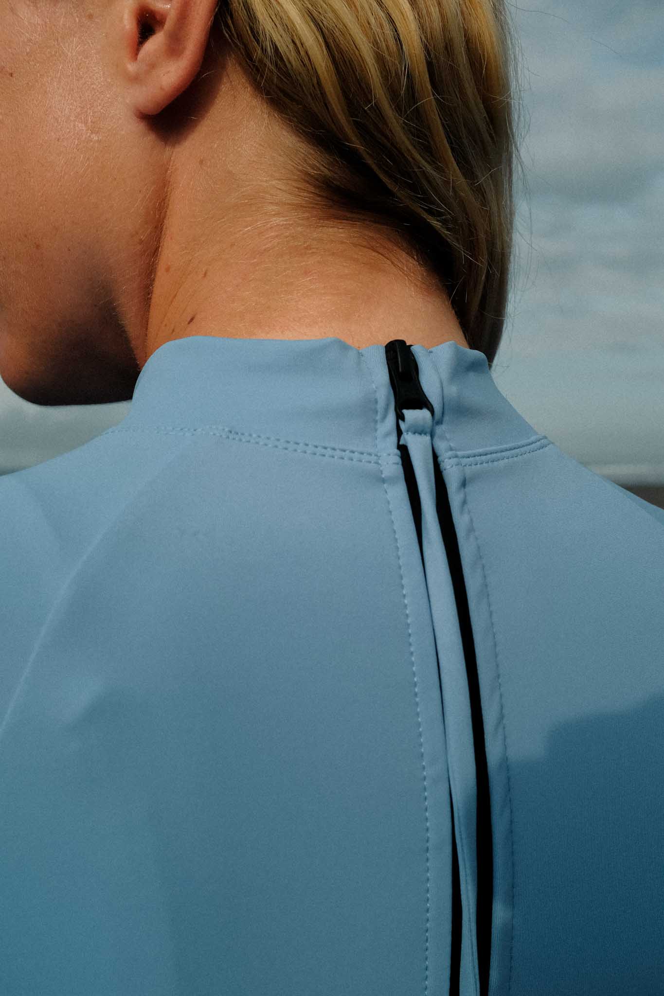 close up of the back of the surf rash guard on a model showing the zipper detail