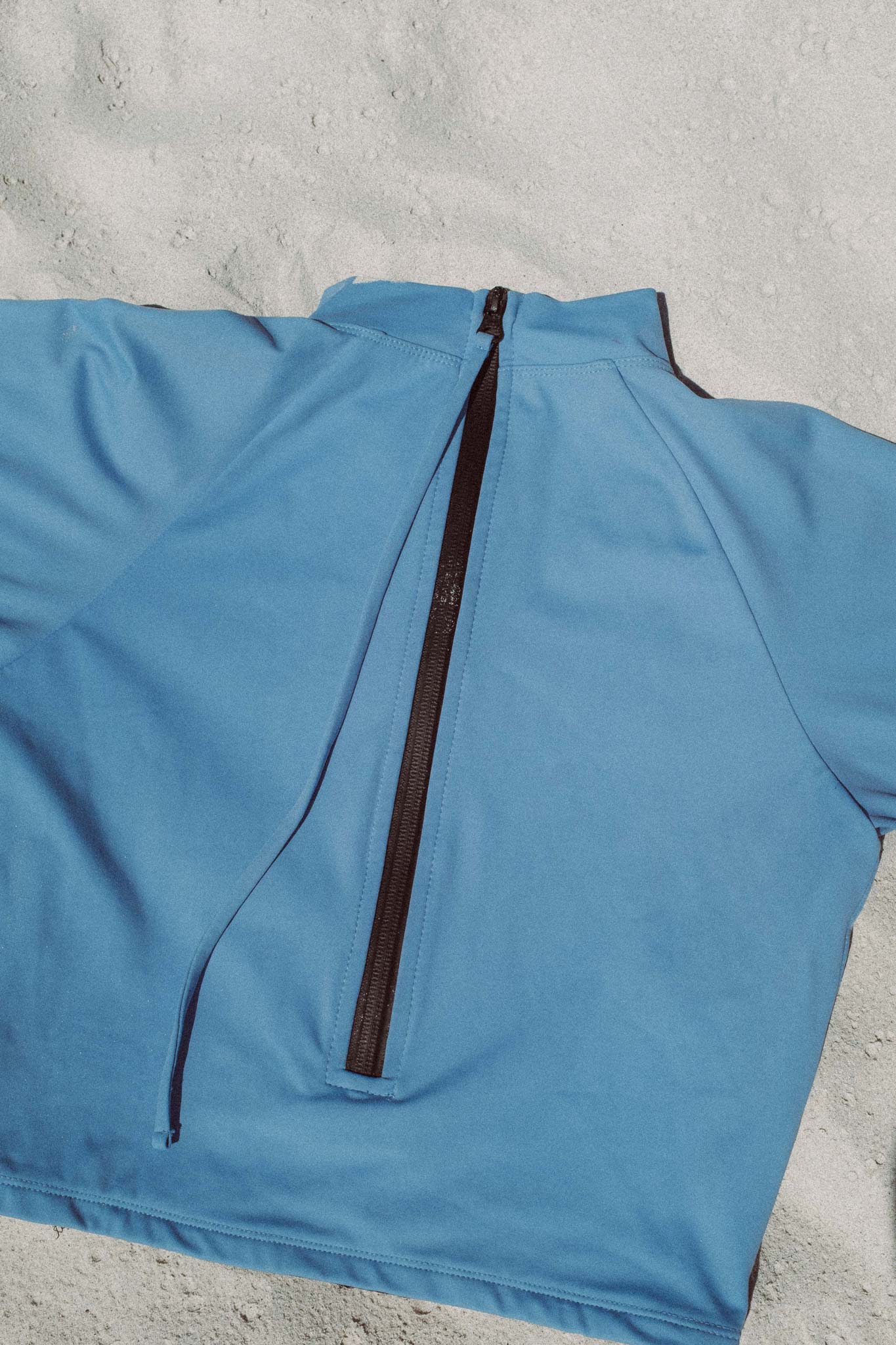 flatlay photo of the putu turtleneck top in blue at the beach