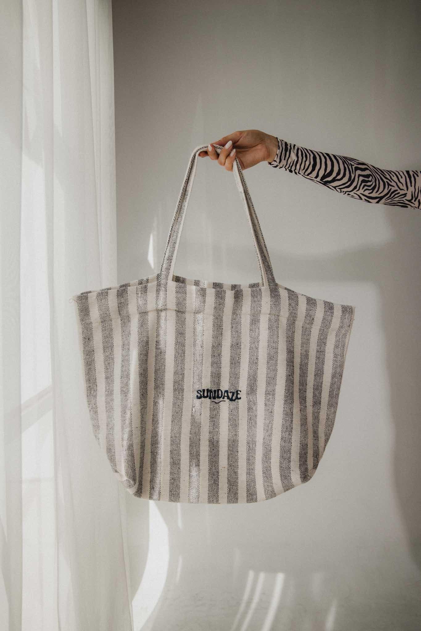 A hand holding the Chapter One Handmade Striped Tote Bag