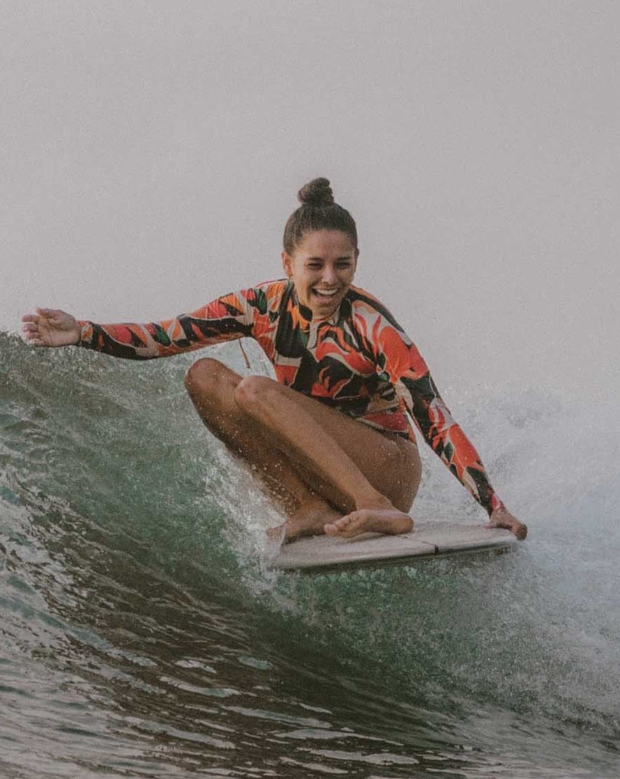 A woman surfing in the Made Long Sleeve One-Piece Surf Spring Suit